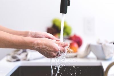a person washing their hands in a kitchen sink