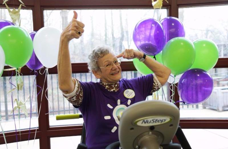 a woman giving a thumbs up at a party with lots of balloons behind her