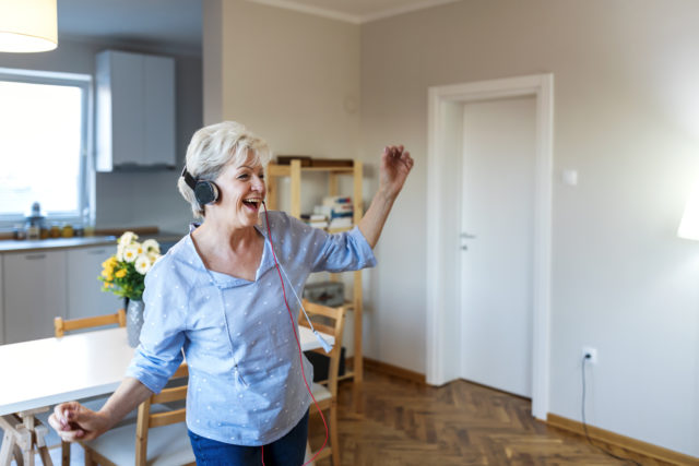 a woman wearing headphones listening to music.Senior woman wearing headphones listening to music and dancing