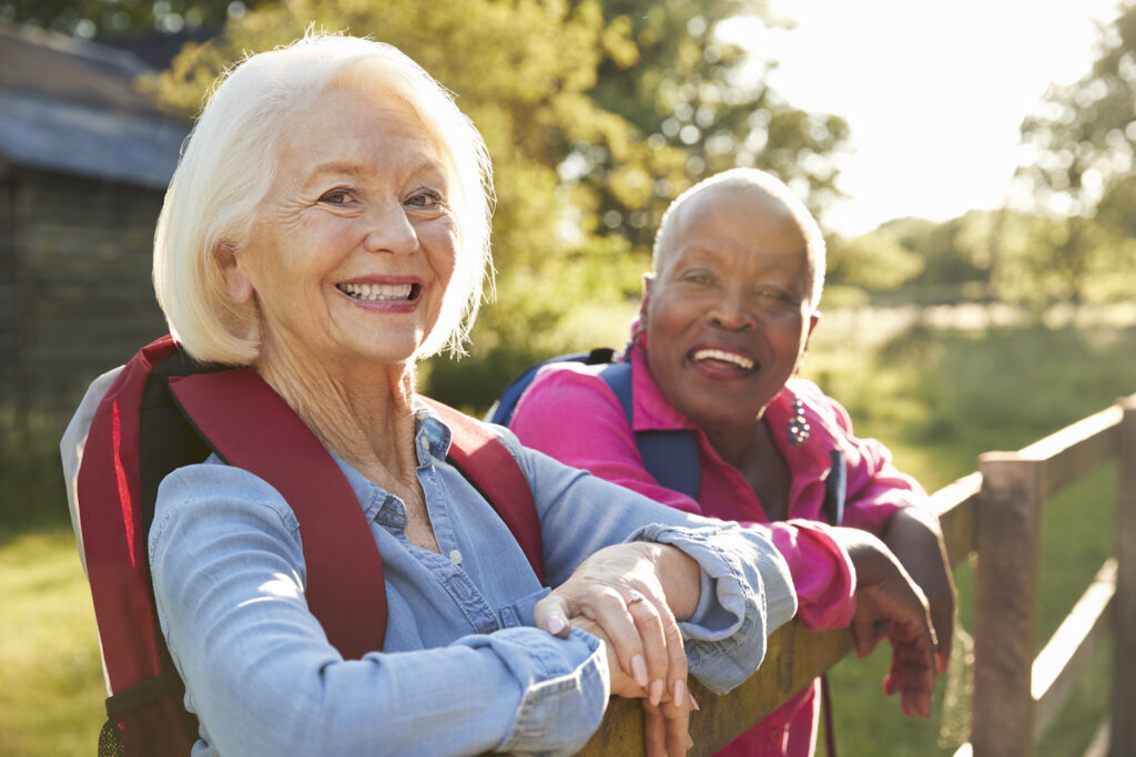two women outside together leaning on a fence